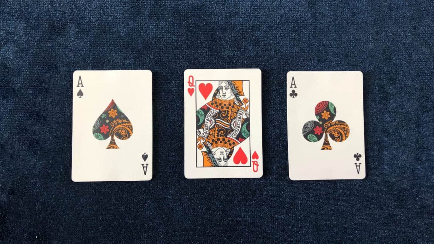 The Ace of Spades, Queen of Hearts and Ace of Clubs from the Dapper Deck Playing Cards are used on a blue close-up mat for an easy card trick